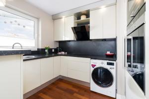 a kitchen with white cabinets and a washer and dryer at Malta Lake Apartment Balcony and Parking by Renters Prestige in Poznań