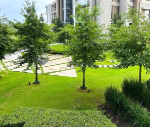 a green park with trees and a building at Menlyn Maine Residences - Kyoto king size xl bed in Pretoria