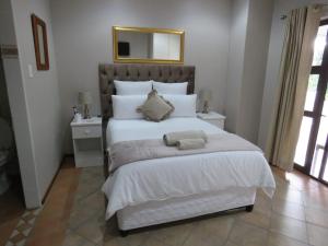 a bedroom with a large white bed with a mirror at Die Stoep in Richards Bay