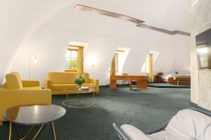 uma sala de estar com cadeiras amarelas e uma mesa em Hotel Kloster Nimbschen 4 Sterne em Grimma