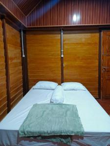 Cama en habitación con pared de madera en Rammang-Rammang Cottage, en Kasijala