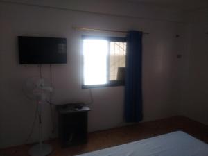 - une chambre avec une fenêtre, une télévision et un ventilateur dans l'établissement Kaye En Em Apartelle, à Puerto Galera