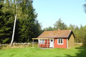 ein kleines rotes Haus auf einem Feld mit Bäumen in der Unterkunft Woody in Brösarp