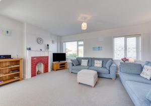 a living room with two blue couches and a fireplace at Marnies View in Sidmouth