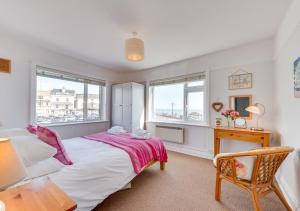 a bedroom with a bed and a desk and windows at Marnies View in Sidmouth