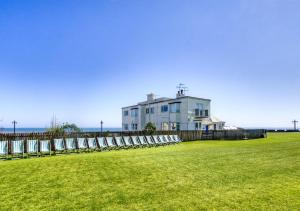 a large white house in a field with the ocean in the background at Marnies View in Sidmouth