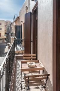 einen Balkon mit einem Tisch und einer Bank auf einem Gebäude in der Unterkunft CASA DORINI in Chania