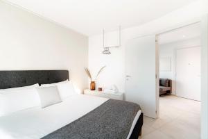 a white bedroom with a large bed and white walls at Kristall 9 by Quokka 360 - modern apartment close to Lugano Center in Massagno