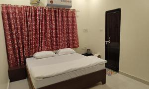 1 dormitorio con 1 cama con cortina roja en BANARAS GUEST HOUSE, en Kakarmatha