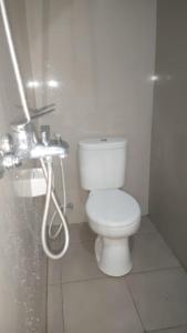 La salle de bains est pourvue d'une douche et de toilettes blanches. dans l'établissement Chandra's guest house, à Pesanggaran