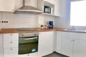 a kitchen with white cabinets and a wooden counter top at Appartement bien situé in Noisy-le-Grand