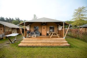 a gazebo with a wooden deck in a yard at Glamping Ackersate in Voorthuizen