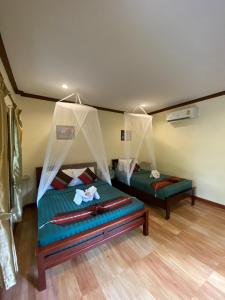 a bedroom with two beds with mosquito nets at Khao Sok River & Jungle Bungalow in Khao Sok National Park