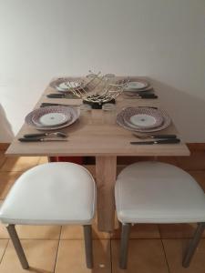 einem Holztisch mit zwei weißen Stühlen und einem Tisch mit Tellern in der Unterkunft appartement city 2 d'Amiens in Amiens