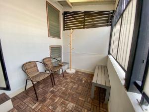 a small balcony with two chairs and a table at Yaksa Private in Bangkok