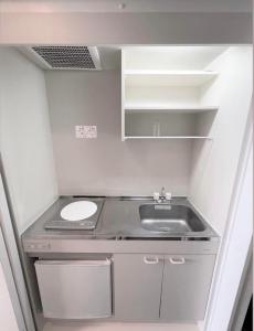uma pequena cozinha com um lavatório e um balcão em ホテル辰巳俱楽部 