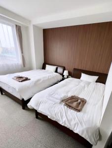 2 bedden in een hotelkamer met witte lakens bij ホテル辰巳俱楽部 