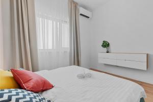 - une chambre blanche avec un lit et des oreillers rouges dans l'établissement Darwin Apartments, à Otopeni