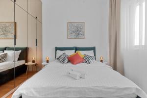- une chambre avec un grand lit blanc et des oreillers colorés dans l'établissement Darwin Apartments, à Otopeni