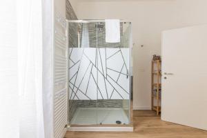 una ducha con puerta de cristal en una habitación en monji apartment en Faenza