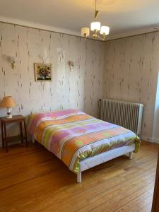 sypialnia z łóżkiem w pokoju z drewnianą podłogą w obiekcie Location maison à Chadron : Haute Loire w mieście Chadron