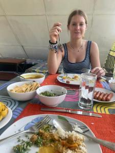 a woman sitting at a table with plates of food at Basecamp - Yala in Yala