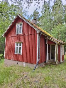 a red house with a door in a field at Topsala MidIsland in Houtskari