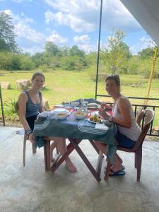 duas mulheres sentadas numa mesa com comida em Basecamp - Yala em Yala
