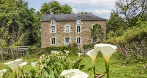 una vecchia casa di mattoni con fiori bianchi di fronte di Le Moulin de Gueuzon a Rochefort-en-Terre