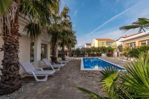 a villa with a swimming pool and palm trees at Luxury Villa Agape Palm Beach Tennisplatz in Privlaka