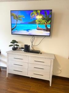 a flat screen tv on a wall above a dresser at Free parking Comfy central Waikiki in Honolulu