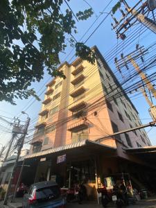 a tall building with cars parked in front of it at Suppamas Mansion ศุภมาส แมนชั่น in Bangkok Yai