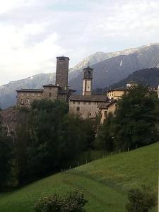 een oud gebouw op een heuvel met bergen op de achtergrond bij Vista panoramica - Chalet rustico in montagna in Valgoglio