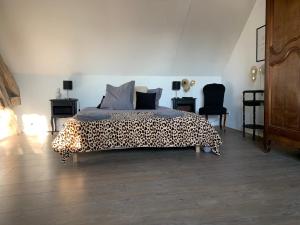 a bedroom with a leopard print bed with two chairs at Le Verger de Pauline in Maslives