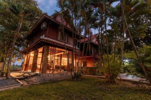 a house with palm trees in front of it at Ganesha Kampot Resort in Kampot