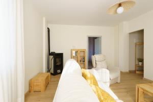 Casa Cauma Apartamento في بني الرزين: غرفة معيشة بيضاء مع أريكة بيضاء وكرسي