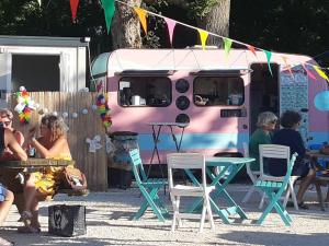 a group of people sitting outside of a pink food truck at nice little cottage F2 class and 3* in Vars