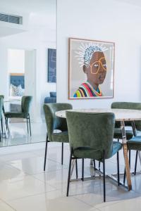 ケープタウンにあるXenia Aparthotel by Totalstayの緑の椅子とテーブル、絵画が飾られたダイニングルーム
