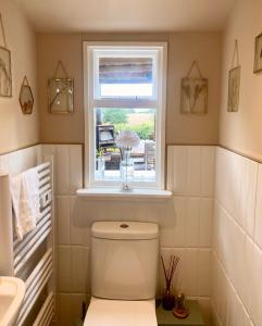 a bathroom with a white toilet and a window at Comfy Cottage Homestay Nr Chelmsford. Free Parking Great Views. 