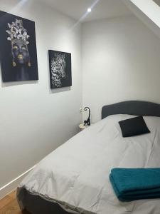 - une chambre blanche avec un lit et des photos sur le mur dans l'établissement agréable, à Noisy-le-Sec