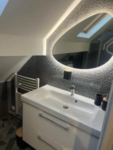 La salle de bains est pourvue d'un lavabo blanc et d'un miroir. dans l'établissement agréable, à Noisy-le-Sec