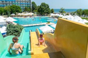 Duas raparigas a escorregar por um escorrega numa piscina. em Safir Blue Resort em Saturn