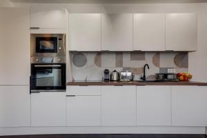 una cocina blanca con armarios y electrodomésticos blancos en 220 Suite Jessy - Superb Apartment in Paris, en París