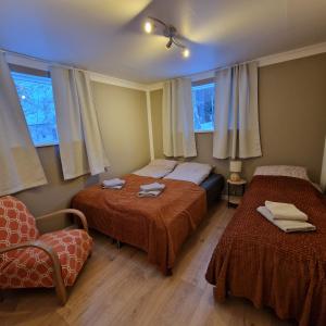 a room with two beds and a chair and windows at Helgimagri Apartment in Akureyri