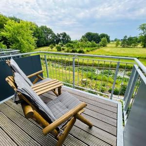 a rocking chair on a deck with a view of a field at Appartement Seerose in Poppenbüll