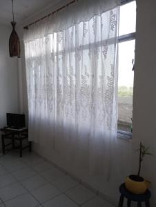 a white curtain in a room with a window at Surf café bar e hospedagem in Rio de Janeiro