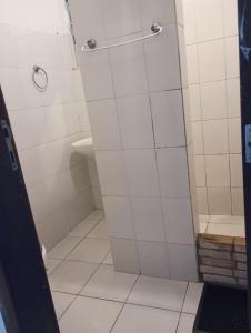 a shower stall in a bathroom with white tiles at Surf café bar e hospedagem in Rio de Janeiro