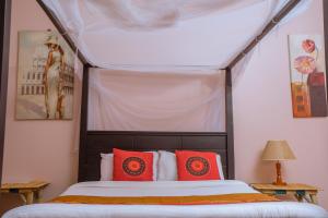 a bedroom with a canopy bed with red pillows at SILVER OAKS HOTEL Boma in Fort Portal