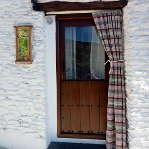 una puerta de una casa con cortinas delante en La Casita, en Capileira