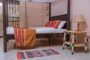 1 dormitorio con 1 cama y 1 mesa con lámpara en SILVER OAKS HOTEL Boma en Fort Portal